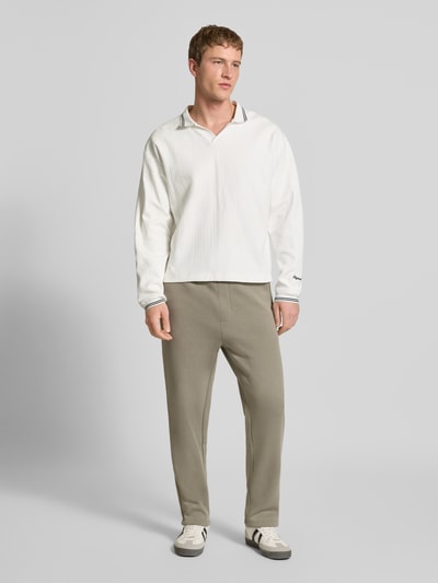 Männermodel trägt Strickpolo aus reiner Baumwolle Modell 'JORNIAGARA' von JACK & JONES, lockere Passform, V-Ausschnitt, Ganzkörperansicht von vorne.