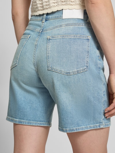 Frauenmodel trägt Jeansshorts mit Eingrifftaschen Modell 'Mari' von OPUS PANTS im Used-Look, Baumwoll-Elasthan-Mix, Regular-Fit, Detailaufnahme Rückansicht. Bundweite bei Größe 36: 36 cm, Innenbeinlänge: 19 cm.