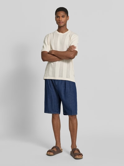 Męski model nosi Regular Fit Jeans-Bermudas aus Baumwoll-Lyocell-Mix Modell 'DENIM' von Armedangels, stylizowana na denim, krój regular fit, aplikacja naszywka z logo, szlufki na pasek, zapięcie na guzik i zamek błyskawiczny, 5 kieszeni, mieszanka bawełny i lyocellu, granatowy denim, powierzchnia gładka, Ganzkörperansicht von vorne.