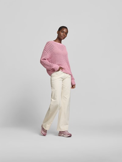 Vrouwenmodel draagt Relaxed Fit Pullover mit Lochmuster van Juvia in roze katoen met gaatjespatroon, ronde hals en elastische boorden, ruglengte maat S 58 cm, vooraanzicht volledige lichaamsopname.