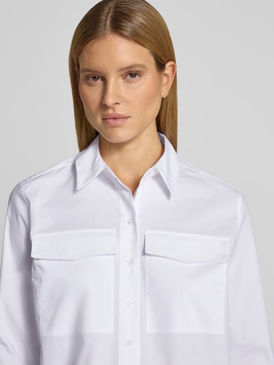 Frauenmodel trägt Regular Fit Hemdbluse mit Brusttaschen von More & More, weiß, glatte Textur, langärmelig, Nahaufnahme Oberkörper.