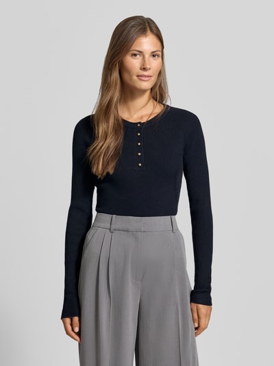 Kobiece modelka nosi Slim Fit Longsleeve aus Strick-Optik od MYON, czarny, imitacja dzianiny, listwa guzikowa, okrągły dekolt, długość tyłu w rozmiarze 36: 60 cm, długość rękawów w rozmiarze 36: 66 cm, widok całej sylwetki z przodu.