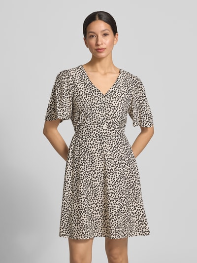Frauenmodel trägt Minikleid aus Viskose mit kurzer Knopfleiste Modell 'GRACE' von Vila, Taillierter Schnitt, V-Ausschnitt, Bindegürtel, cremefarben mit schwarzen Punkten, Rückenlänge 87 cm, Brustweite 46 cm, Ärmellänge 25 cm, Ganzkörperansicht von vorne.