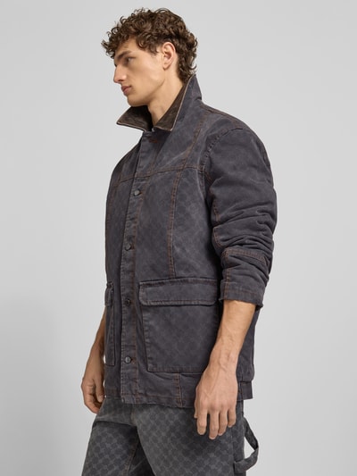 Männermodel trägt Jacke mit echtem Rindsleder-Besatz von DAILY PAPER, reine Baumwolle, Relaxed Fit, Knopfleiste, Ganzkörperansicht von vorne.