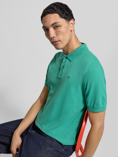 Männermodel trägt Regular Fit Poloshirt aus pure katoen van Tommy Jeans, look effen, logostitching, piqué, korte mouw, ganzkörperansicht von vorne.