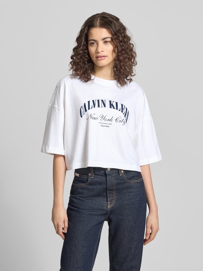 Frauenmodel trägt Cropped T-Shirt mit Logo-Print von Calvin Klein Jeans, weiß, reine Baumwolle, Rundhalsausschnitt, Ganzkörperansicht von vorne