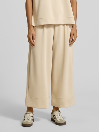 Frauenmodel trägt Wide Leg Sweatpants aus Modal-Mix von Rich & Royal in Beige, weite Form, elastischer Bund, Bundfalten, Seitentaschen, Nahaufnahme Oberschenkel bis Schuhe.
