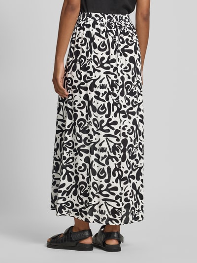 Frauenmodel trägt Maxi-Rock aus reiner Viskose Modell 'BARRI' von Pieces mit Optik:Allover-Muster in Schwarz-Weiß, Elastisch, Schmal, Maxi-Länge, Ganzkörperansicht Rückansicht.