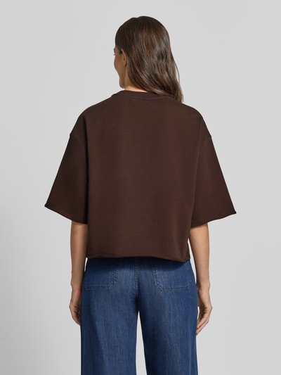 Frauenmodel trägt Cropped Boxy Fit Sweatshirt mit Label-Stitching von Smith and Soul in Dunkelbraun zu Jeans, Ganzkörperansicht Rückansicht. Baumwoll-Elasthan-Mix, 1/2-Arm, Rundhalsausschnitt, Boxy Fit, Cropped.