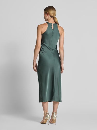 Frauenmodel trägt Abendkleid aus Satin mit Rundhalsausschnitt Modell 'RAVENNA' von VILA in dunklem Grün, glatte Oberfläche, Ganzkörperansicht Rückansicht.
