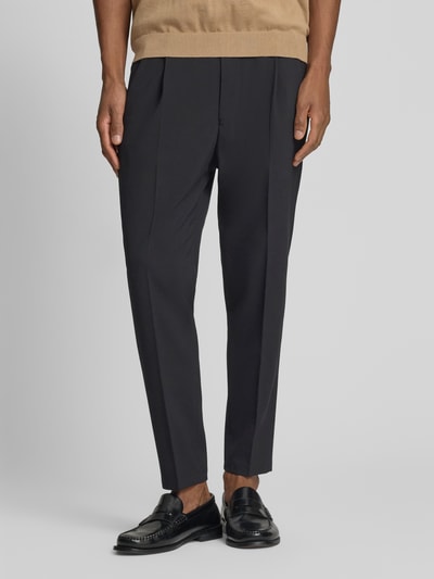 Männermodel trägt Hose mit Eingrifftaschen Modell 'CHASY' von Drykorn, schwarz, Tapered Fit, glatte Struktur, Ganzkörperansicht von vorne.