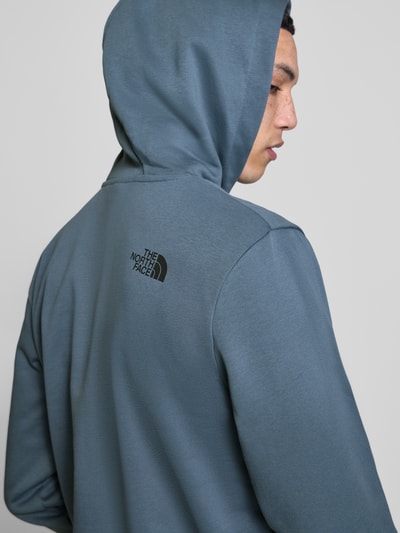 Männermodel trägt Regular Fit Hoodie mit Logo-Print von The North Face in Blau mit Kapuze und Logo, Nahaufnahme Rückansicht, Baumwoll-Mix.