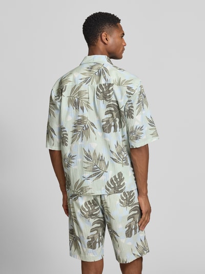 Männermodel trägt Relaxed Freizeithemd mit floralem Allover-Print von Lindbergh in Grün-Beige, Halbarm, strukturierte Baumwolle, Ganzkörperansicht Rückansicht.