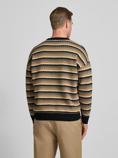 Männermodel trägt Strickpullover mit Rundhalsausschnitt Modell 'Neelio' von Drykorn, Baumwoll-Woll-Mix, Relaxed-Fit, Rückenlänge 70 cm, Streifen in Beige, Schwarz und Braun, Ganzkörperansicht Rückansicht.