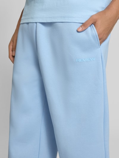 Männermodel trägt Straight Fit Sweatpants Baumwoll-Mix von REVIEW in Hellblau, Label-Print, seitliche Eingrifftaschen, Nahaufnahme Oberkörper.