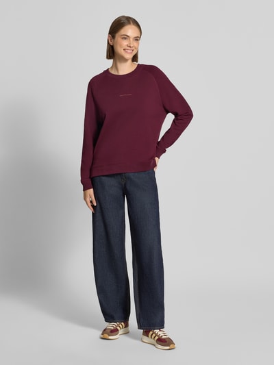 Frauenmodel trägt Regular Fit Sweatshirt aus reiner Baumwolle von Marc O'Polo in Dunkelrot, kombiniert mit blauer Jeans, Ganzkörperansicht von vorne, Damen Sweatshirt von Marc O'Polo DENIM.