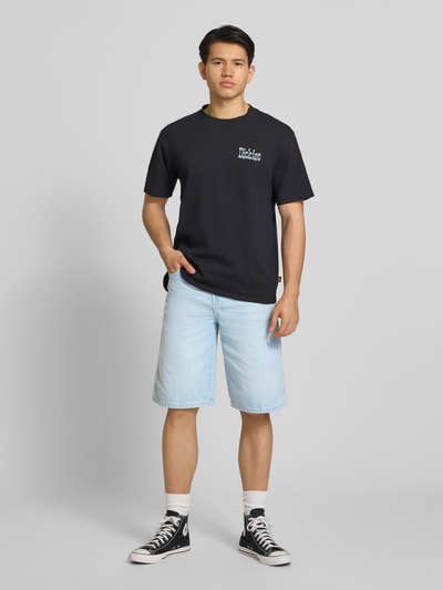 Männermodel trägt Loose Fit Bermudas mit Eingrifftaschen von Dickies in hellem Denim aus Reine Baumwolle, Ganzkörperansicht von vorne.