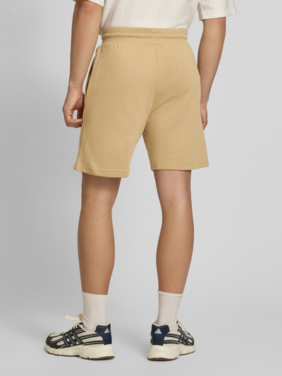 Mężczyzna nosi Regular Fit Shorts mit Eingrifftaschen von The North Face, mieszanka bawełny, beżowe, szerokość w rozmiarze M: 40 cm, długość wewnętrzna nogawki: 18 cm, widok całej sylwetki z tyłu.