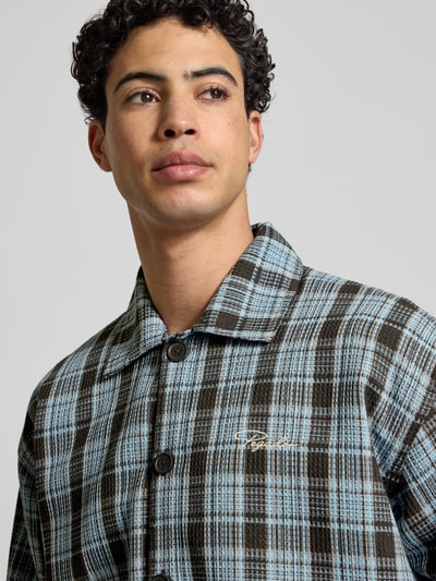 Männermodel trägt Regular Fit Freizeithemd mit Label-Stitching von Pegador, Modell 'Rupit', Kentkragen, Nahaufnahme Oberkörper.