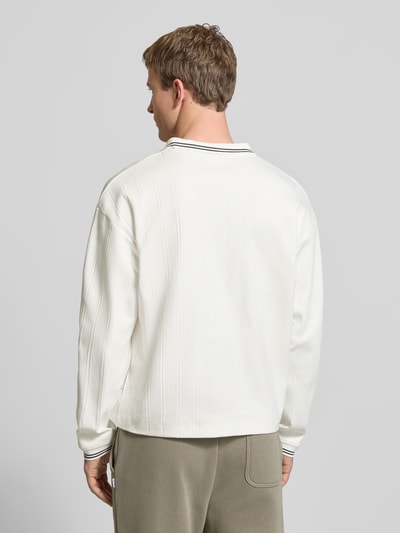 Männermodel trägt Strickpolo aus reiner Baumwolle Modell 'JORNIAGARA' von JACK & JONES in Weiß, elastische Ärmelabschlüsse, Lockerer-Schnitt, Kontrast-Umlegekragen, Label-Detail, Rückenlänge bei Größe M 64 cm, Ganzkörperansicht Rückansicht.