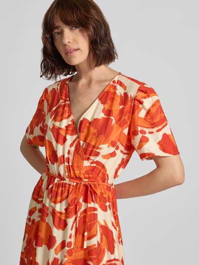 Vrouwenmodel draagt midi-jurk van Viscosemix, getailleerd model met V-hals in wikkellook, strikceintuur, Model 'Si44ciliana' van ZABAIONE, dames midi-jurk, ruglengte maat S 109 cm, borstwijdte maat S 49 cm, mouwlengte maat S 27 cm, oranje-rode bloemenprint, gladde textuur, Nahaufnahme bovenlichaam.