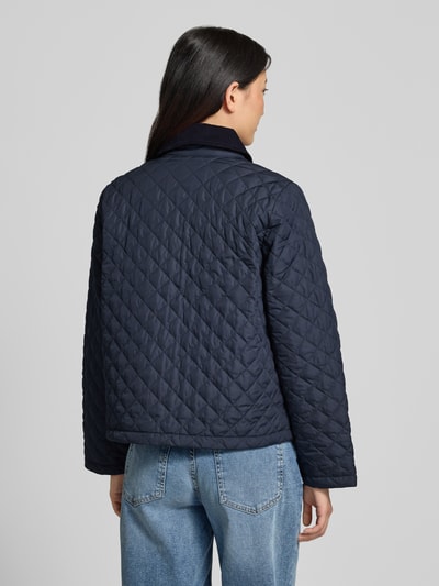 Modelka kobieca ma na sobie granatową kurtkę pikowaną Regular Fit Steppjacke mit aufgesetzten Seitentaschen Modell 'AYLESBY' od Barbour, damska kurtka pikowana, widok całej sylwetki z tyłu.
