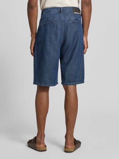 Männermodel trägt Regular Fit Jeans-Bermudas aus Baumwoll-Lyocell-Mix Modell 'DENIM' von Armedangels w stylizowanej na denim optyce, naszywka z logo, szlufki na pasek, zapięcie na guzik i ukryty zamek błyskawiczny, 5 kieszeni, mieszanka bawełny i lyocellu, Ganzkörperansicht Rückansicht.