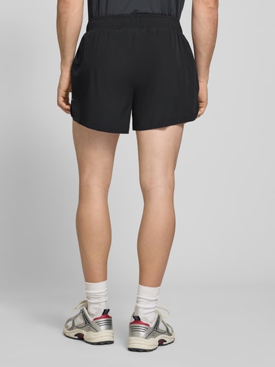 Männermodel trägt schwarze Herren Shorts mit elastischem Bund, Modell 'ERUDITO' von Ellesse, Material-Mix mit Stretch-Anteil, Regular-Fit, Ganzkörperansicht Rückansicht.