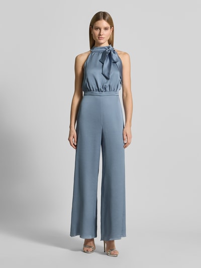 Kobiece modelka nosi kombinezon Regular Fit Jumpsuit mit Zierschleife od Swing, fakturowany wzór, stójka, ozdobna kokarda, krój regular fit, bez rękawów, taliowany, długość tyłu w rozmiarze 36: 38 cm, szerokość w rozmiarze 36: 45 cm, całkowita długość w rozmiarze 36: 150 cm, długość wewnętrzna nogawki w rozmiarze 36: 83 cm, niebieski odcień, widok całej sylwetki z przodu