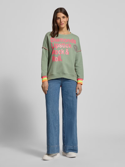 Frauenmodel trägt Oversized Sweatshirt mit gerippten Abschlüssen von miss goodlife aus reiner Baumwolle, Statement-Print, okrągły dekolt, krój oversized, prążkowane wykończenia, jasne kolory, Ganzkörperansicht von vorne