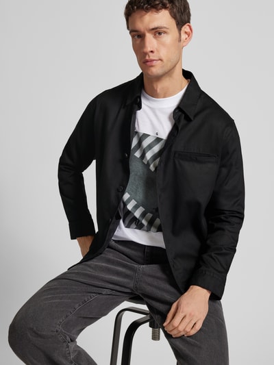 Männermodel trägt Regular Fit Hemdjacke aus Lyocell-Baumwoll-Mix Modell 'ENOCK' von HUGO, unifarben schwarz, Ganzkörperansicht von vorne.