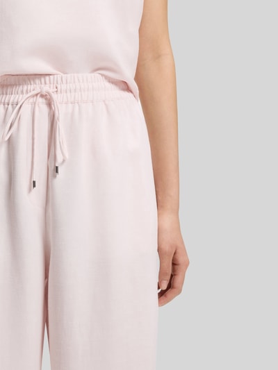 Vrouwenmodel draagt Loose Fit Leinenhose aus Lyocell-Leinen-Mix Modell 'TAVATI2_TI' van BOSS, effen kleuren, mix van lyocell en linnen, elastische boord, tunnelkoord, labelapplicatie van metaal, zij-steekzakken, detailopname rechterzijde taille