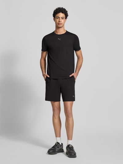 Männermodel trägt schwarze Shorts mit Logo Modell 'CLOUDSPUN 7' von PUMA PERFORMANCE aus Material-Mix mit Lyocell-Anteil, Regular-Fit, elastischer Bund mit Tunnelzug, Herren, Ganzkörperansicht von vorne.