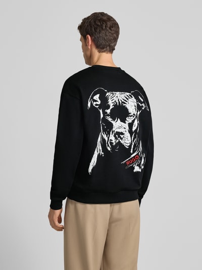 Männermodel trägt Regular Fit Sweatshirt aus reiner Baumwolle Modell 'DUBRAXO' von HUGO, Optik: Unifarben, Motiv-Print, Ganzkörperansicht Rückansicht.