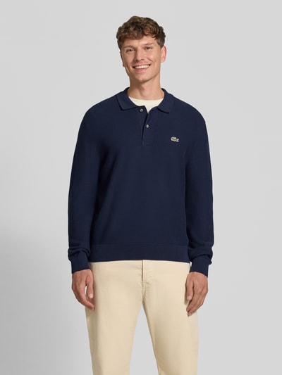 Männermodel trägt Regular Fit Poloshirt aus reiner Baumwolle von Lacoste in Dunkelblau, glatte Textur, Ganzkörperansicht von vorne, Herren Poloshirt von Lacoste.