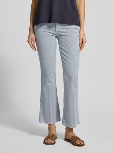 Frauenmodel trägt Jeans mit Eingrifftaschen Modell 'SHAKIRA' von Brax aus Baumwoll-Mix mit Stretch-Anteil, hellblau-weiß gestreift, verkürzte Passform, Knopf- und Reißverschluss, Ganzkörperansicht von vorne.