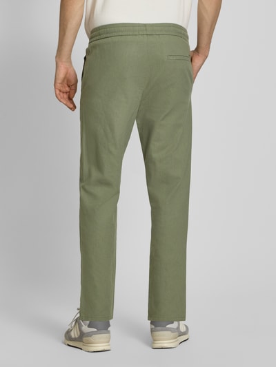 Männermodel trägt Tapered Leinenhose aus Baumwoll-Leinen-Mix Modell 'LINUS' von Only & Sons in Melange-Optik mit elastischem Bund, seitlichen Eingrifftaschen und Gesäßtasche, Ganzkörperansicht Rückansicht.