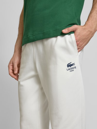 Lacoste Spodnie dresowe o kroju tapered fit z nadrukiem z logo model ‘HERITAGE’ Złamany biały 3