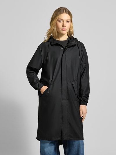 Modelka nosi Regular Fit Parker mit Kapuze Modell 'Fishtail' od Rains, czarny, kieszenie z patką, elastyczne zakończenia rękawów, długość tyłu 104 cm, szerokość ramion w rozmiarze S 45 cm, szerokość klatki piersiowej w rozmiarze S 55 cm, długość rękawów w rozmiarze S 65 cm, widok całej sylwetki z przodu.