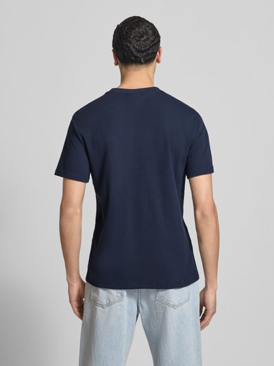 Männermodel trägt Regular Fit T-Shirt mit Logo-Patch von Calvin Klein Jeans aus Baumwoll-Mix in Dunkelblau mit Strukturmuster, Ganzkörperansicht Rückansicht.