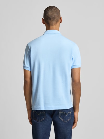 Mężczyzna model nosi Regular Fit Poloshirt aus reiner Baumwolle von Lacoste, efekt: jednolity kolor, krój regular fit, wyhaftowane logo, kołnierzyk polo, krótki rękaw, prążkowane zakończenie rękawów, dół z rozcięciami po bokach, wykończenie: pika, materiał: czysta bawełna, widok całej sylwetki z tyłu.