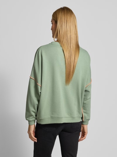 Frauenmodel trägt Oversized Sweatshirt mit Motiv-Print Modell 'Heartface' von miss goodlife in Mintgrün, reine Baumwolle, lockerer Schnitt, elastische Abschlüsse, Ganzkörperansicht Rückansicht.