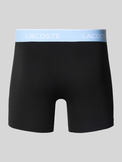Produktfoto, Trunks aus Baumwoll-Mix im 3er-Pack von Lacoste, einfarbig schwarz mit hellblauem, elastischem Label-Bund, glatte Textur.