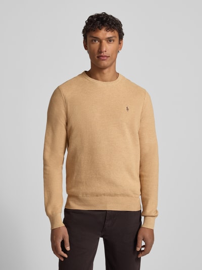 Męski model nosi Sweter z dzianiny z wyhaftowanym logo od Polo Ralph Lauren, bawełna, krój regular fit, prążkowane wykończenia, okrągły dekolt, beżowy, długość tyłu 72 cm, długość rękawów 69 cm, całkowity widok z przodu.
