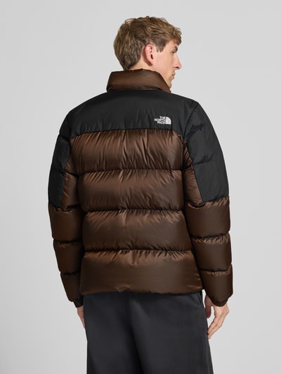 Männermodel trägt Regular Fit Jacke mit Daunen-Feder-Füllung Modell 'Diabolo' von The North Face, Stepp-Optik in Braun und Schwarz, Logo-Stitching, Ganzkörperansicht Rückansicht.