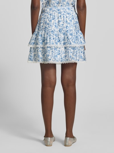 Frauenmodel trägt Ausgestellter Rock aus Viskose-Mix Modell 'BLISS' von Vero Moda mit Florales-Allover-Muster, Popeline, Mini-Länge, Elastisch, Ganzkörperansicht Rückansicht.