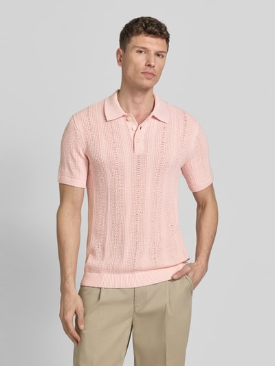 Męski model nosi Slim Fit Poloshirt mit Knopfleiste od Jack & Jones Premium w jasnoróżowym kolorze, bawełniany miks, krój slim fit, kołnierzyk polo, zapięcie na guziki, długość pleców w rozmiarze M: 72 cm, widok całej sylwetki z przodu.