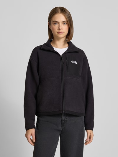 Frauenmodel trägt Regular Fit Fleecejacke mit Stehkragen Modell 'YUMIORI' von The North Face in Schwarz mit Logo-Stitching, Ganzkörperansicht von vorne.