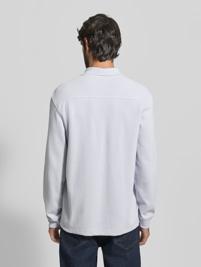 Männermodel trägt Regular Fit Poloshirt aus Baumwoll-Mix Modell 'PETEMPESTOLONG' von BOSS Orange, Unifarben, Rückenansicht, Piqué-Struktur.