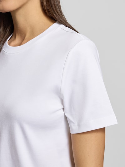 Frauenmodel trägt T-Shirt mit geripptem Rundhalsausschnitt von comma in Weiß, glatte Struktur, Regular Fit, Nahaufnahme Oberkörper.